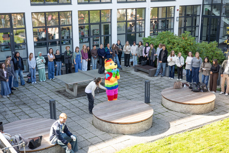 Erstsemester werden im Innenhof vom Asta Stupa Maskottchen (Monster mit buntem Fell) begrüßt