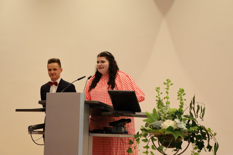 Ein Absolvent und eine Absolventin am Redepult