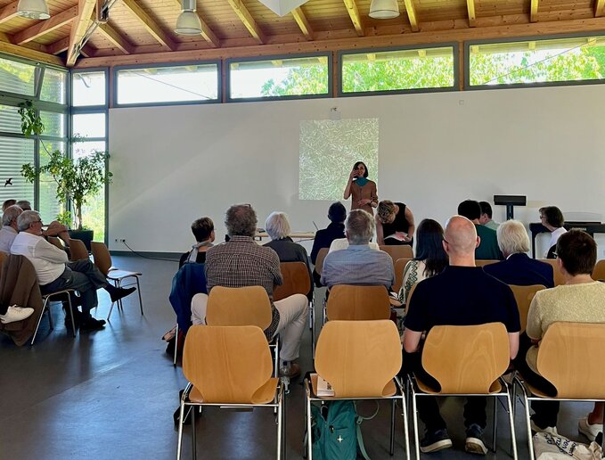 Zuschauer sitzen im Vortragssaal, mit dem Rücken zur Kamera.