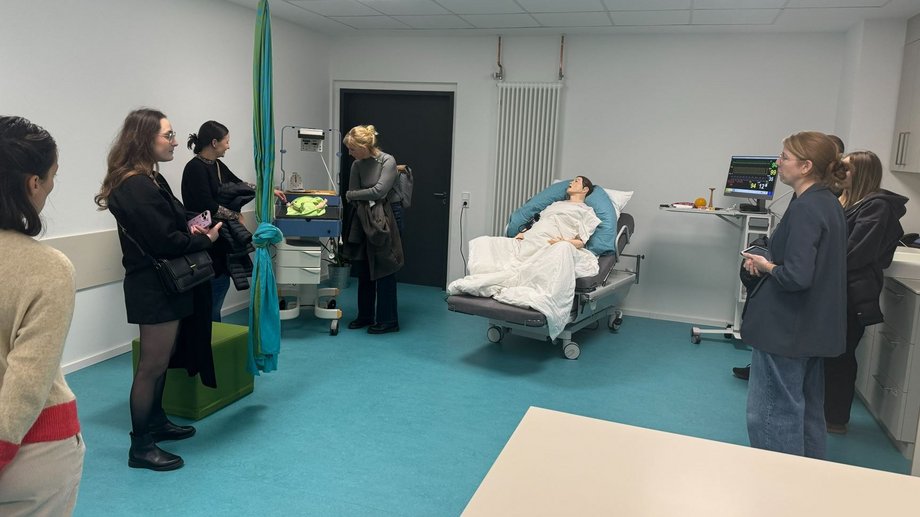 Studieninteressierte besichtigen das SkillsLab der katho. Vor ihnen steht ein Pflegebett mit einer lebensgroßen Puppe.
