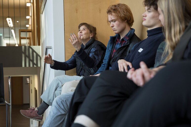 Vier Menschen auf einer Bank. Sie sind von der Seite fotografiert. Die letzte Person erzählt etwas und gestikuliert dabei mit ihren Händen in der Luft.