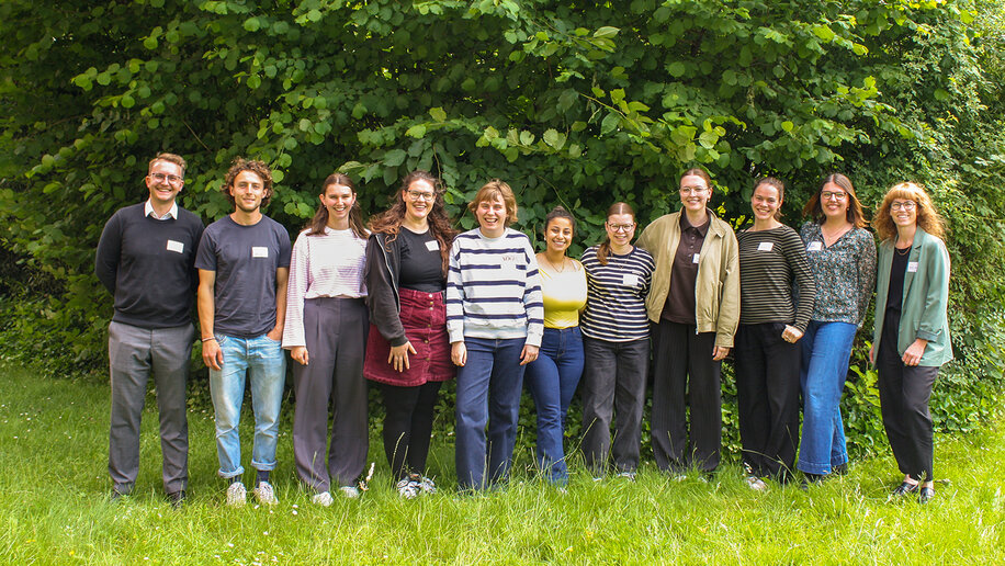Gruppenbild mit 11 Studierenden und Projektmitarbeitenden, auf einer Wiese vor einem großen Busch.