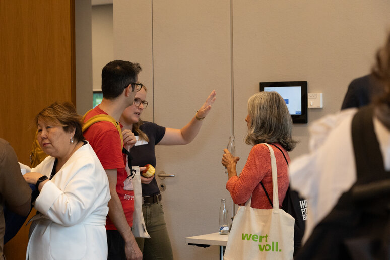 Menschen stehen sich gegenüber und tauschen sich auf der Tagung aus. 