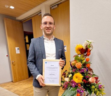 Ahmad Sabsabe zeigt seine Urkunde des DAAD-Preises 2022 auf der Dienstbesprechung in Paderborn