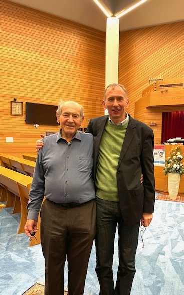 Bernward Robrecht steht rechts auf dem Foto und legt seinen rechten Arm um Yecheskels Schulter. Beide stehen frontal zur Kamera und lächeln ihr entgegen.