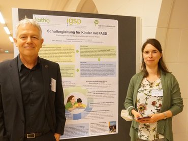 Prof. Dr. Johannes Jungbauer mit Projektmitarbeiterin Angela Sieger vor dem prämierten Projektposter. (Foto: C. Kurlemann / DVSG).