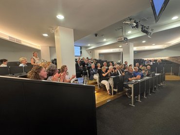 Gäste sitzen im Hörsaal und applaudieren