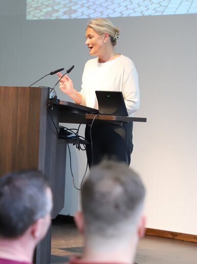 Die Bürgermeisterin steht am Pult auf der Bühne und begrüßt die neuen Studierenden.