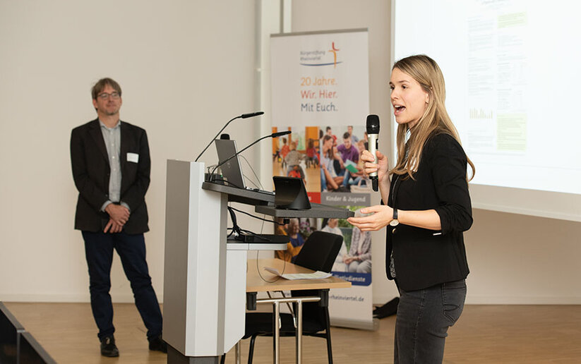 Promovendin Franziska Sawitzki steht am Redepult und spricht. Links im Hintergrund steht eine weitere Person. 