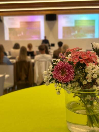 Eine kleine Blumenvase auf einem Stehtisch mit grüner Tischdecke