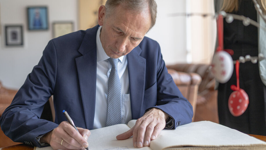 Kanzler Bernward Robrecht sitzt am Tisch und trägt sich ins Gästebuch der Hochschule ein.