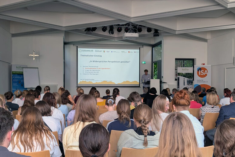Dominik Farrenberg steht vor der gefüllten Aula am Rednerpult.