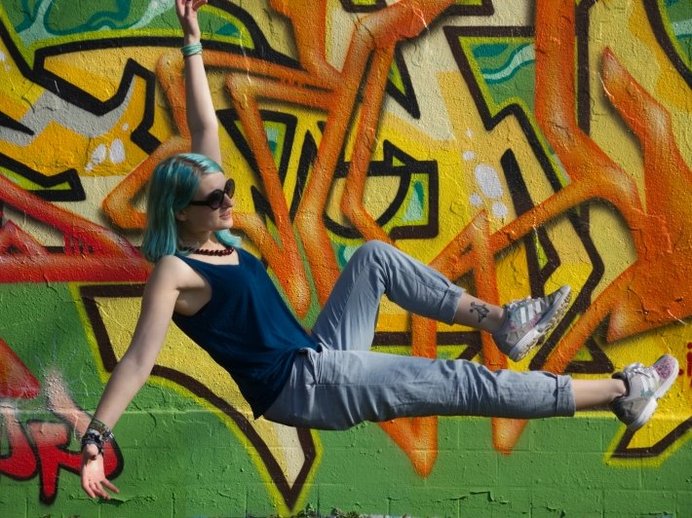Junge Frau posiert vor Wand mit buntem Graffiti