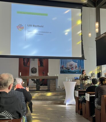 Die stellvertretende Generalsekretärin der Bundeschülerkonferenz, Lilli Berthold, steht auf einer Bühne vor Publikum und spricht Grußworte bei der Eröffnungsveranstaltung.