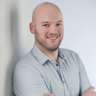 Marvin Hackfort steht im Raum und lächelt.