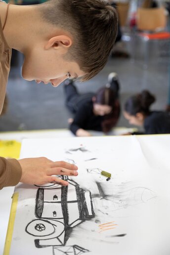 Ein Schüler malt mit Kohle ein Auto.