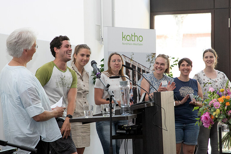 Professorin und Chormitglieder auf der Bühne.