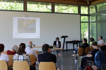 Viele Besucher sitzen in einem hellen Saal und hören einem Vortrag zu.