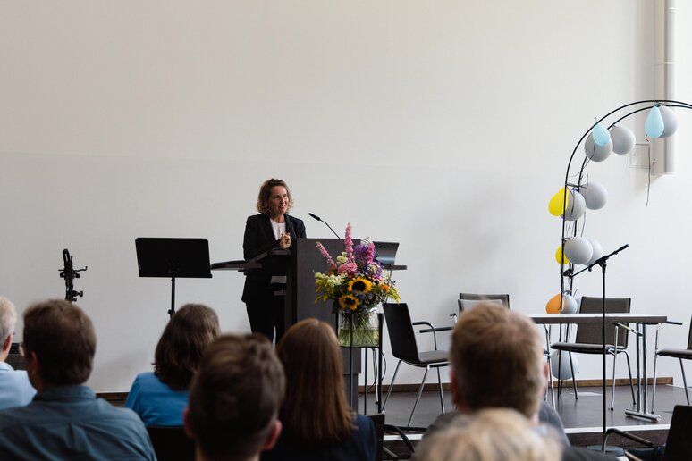 Die Dekanin hält am Rednerpult auf der Bühne eine Rede.