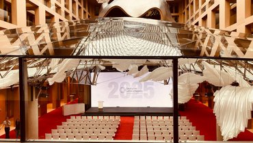 Blick in die Halle eines modernen Gebäudes. Auf rotem Teppich stehen weiße Stuhlreihgen, im Hintergrund ist eine Leinwand mit der Aufschrift "Deutscher Lehrkräftepreis 2025".