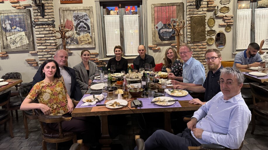 Eine Gruppe von Menschen in einem georgischen Restaurant mit gedecktem Tisch.