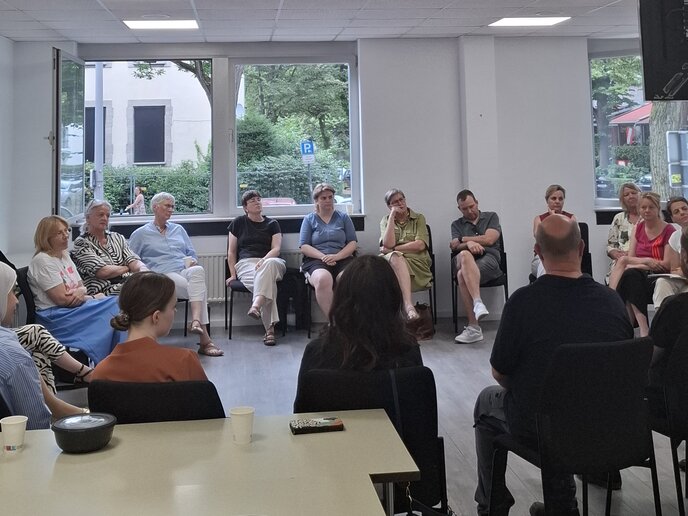 Ca. 15 Menschen sitzen in einem Seminarraum im Stuhlkreis.