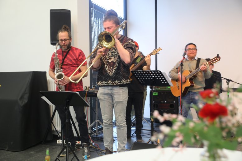 Die Bandmitglieder stehen verschiedene Instrumente spielend auf der Bühne.