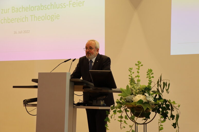 Professor Sander steht am Redepult und begrüßt die Anwesenden