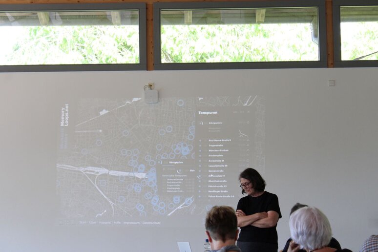 Eine Frau steht vor einer Leinwand auf der eine Karte projiziert ist.