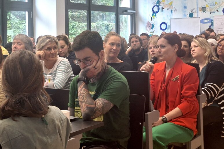 Dr.in Rita Molzberger sitzt im Publikum und stellt mit Mikrofon in der Hand eine Fachfrage.