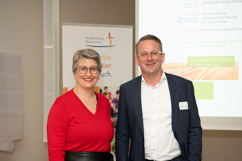 Prof. Dr. Oliver Thiemann und Agnes Leinweber stehen nebeneinander und lächeln in die Kamera.