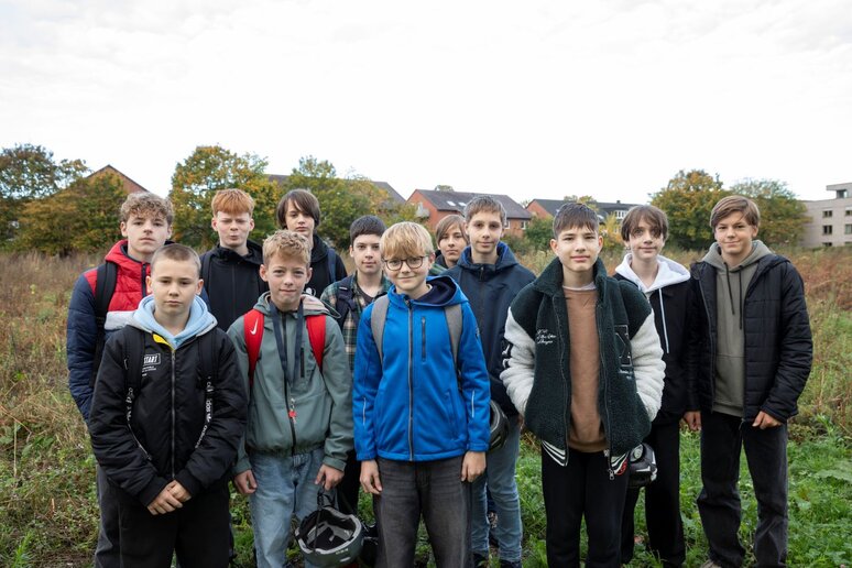 Eine Gruppe Schüler steht auf einer Wiese aufgereiht für ein Foto.