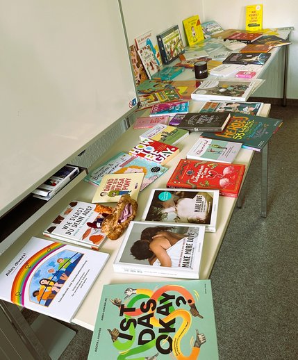Auf einem Tisch liegen viele bunte Bücher zum Thema Sexuelle Bildung.