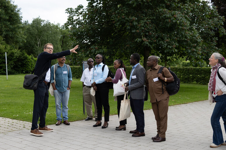 Eine Gruppe von Menschen steht im katho Garten Paderborn und eine Person erklärt die Umgebung. 