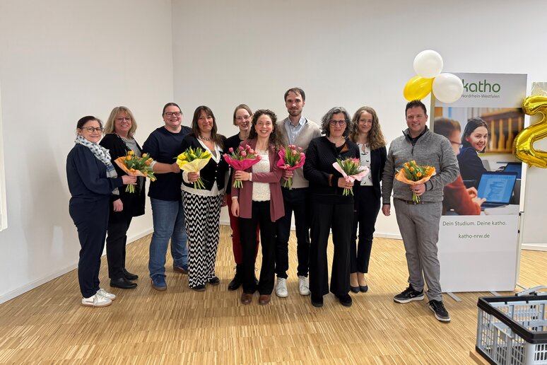 Die Lehrenden stehen aufgereiht mit Blumen