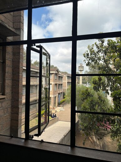 Blick von innen aus einem geöffneten Fenster auf mehrere moderne Gebäude.