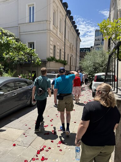 Menschen laufen in einer Straße mit Rosenblättern auf dem Boden.