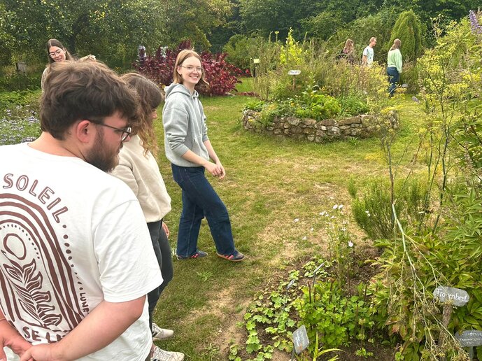 Teilnehmer_innen schlendern durch einen Kräutergarten. 