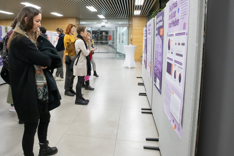 Anwesende gehen durch die Ausstellung und schauen sich die Plakate an.