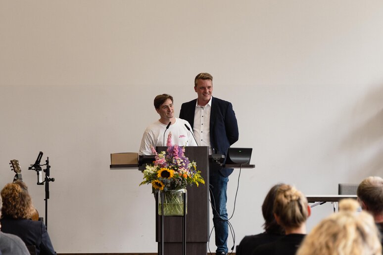 Zwei Studierende halten am Rednerpult auf der Bühne eine Rede. 