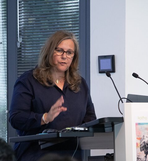 Silvia Hamacher spricht stehend am Rednerpult und hebt dabei eine Hand.