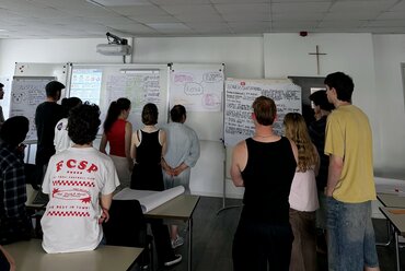 Studierende stehen an Flipcharts an denen zu verschiedenen Ländern Informationene zusammengetragen wurden.