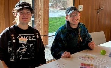 Zwei männliche katho-Studierende sind zu sehen, sie sitzen an einem Tisch und lachen fröhlich 