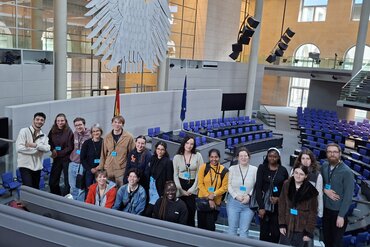 Gruppenfoto der Austauschstudierenden im Deutschen Bundestag vor dem Reichsadler im Plenarsaal..