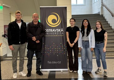 Fünf Personen stehen in der Eingangshalle der Universität Ostrava neben einem Banner der Ostravská univerzita.