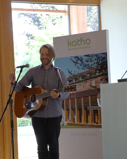 Der Musiker Carsten Mentzel singt mit der Gitarre ein Lied.