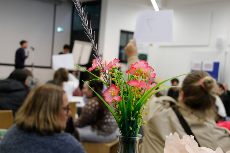 Jemand performt stehend auf der Bühne, die Zuschauer sitzen alle.