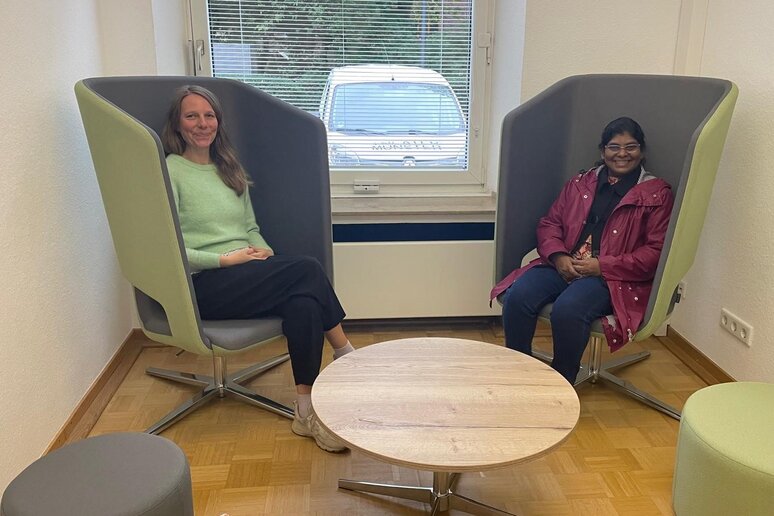 Zwei Personen sitzen auf futuristisch-modernen Ohrensesseln.