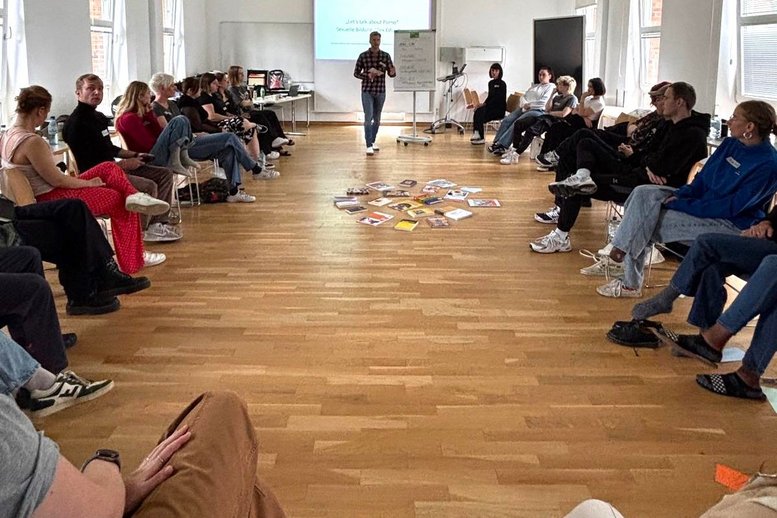 Eine Gruppe von Studierenden sitzen links und rechts. Vorne referiert ein Professor.