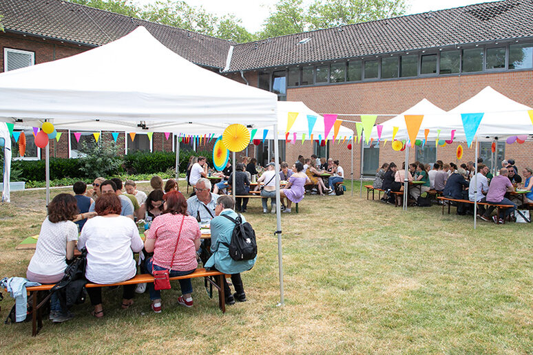 Menschen auf Bierbänken unter Pavillons.